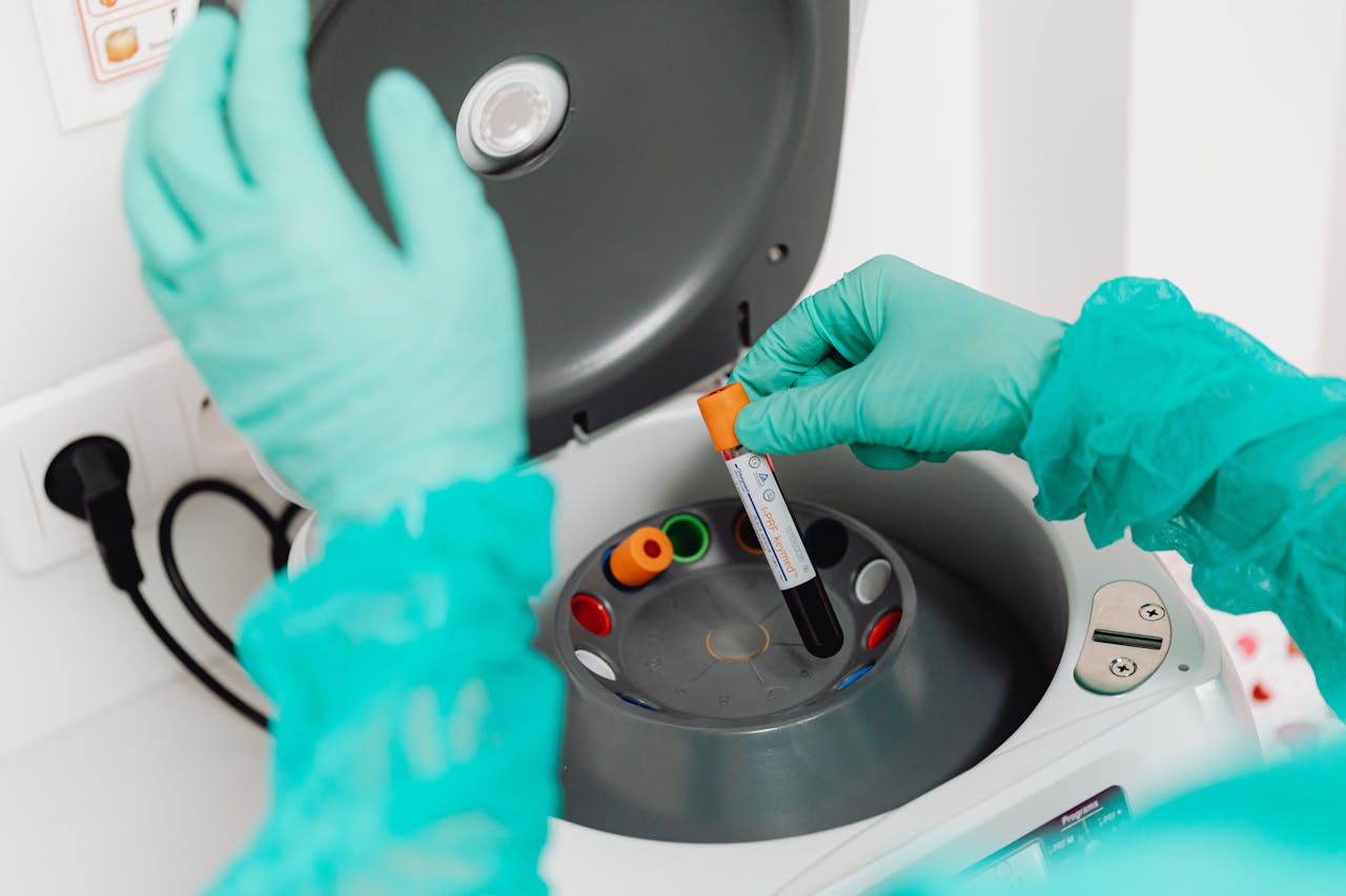 service-04 A lab technician wearing gloves uses a centrifuge for blood analysis in a modern laboratory setting.